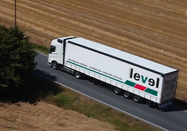 Kamion firmy Jiří Žabka – LEVEL jede po silnici mezi poli
