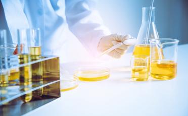 Výzkumník provádějící analýzu oleje s pipetou a Petriho miskou