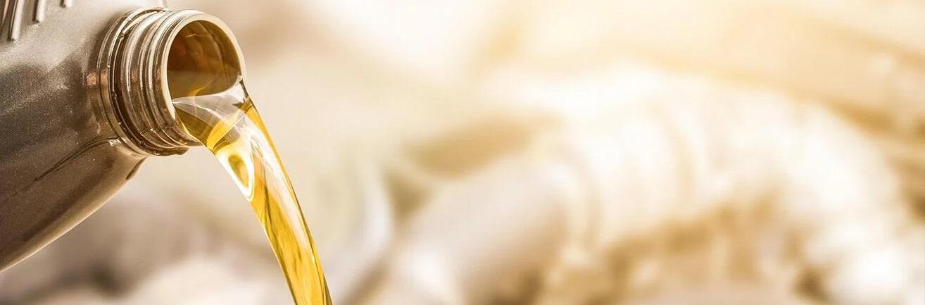 Detail hrdla balení oleje na zlatém pozadí, ze kterého je naléván olej