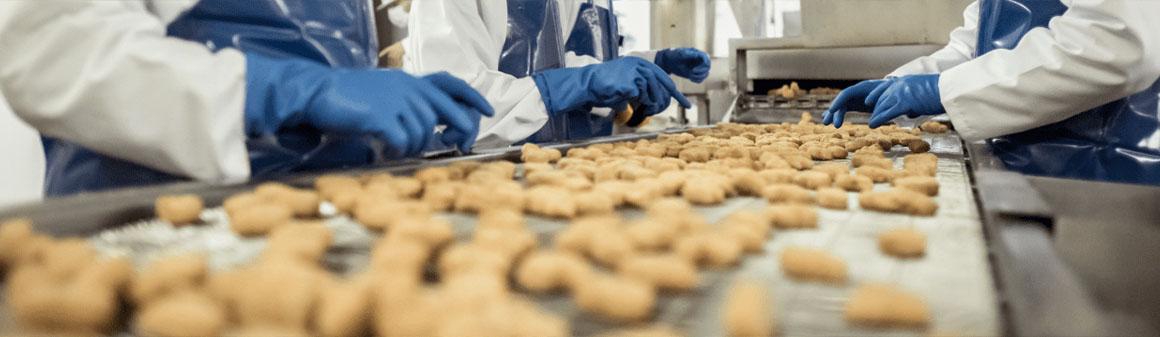 Pracovníci kontrolují sušenky na pohyblivém pásu