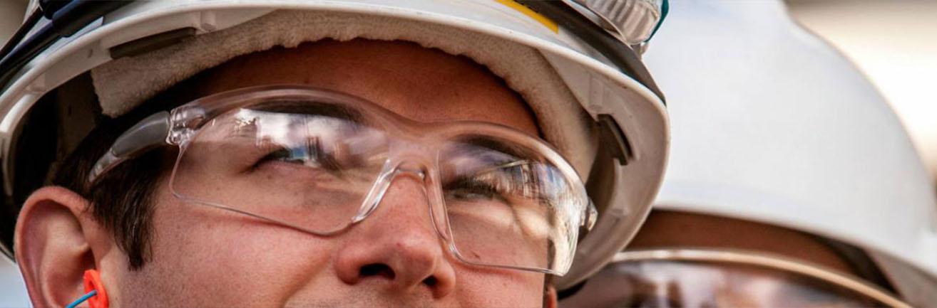 Detail pracovníka TotalEnergies s ochrannými brýlemi a helmou